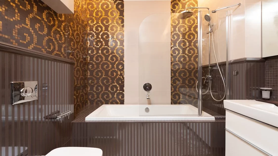 Classic hotel bathroom with a built-in bathtub, patterned wall tiles, and a modern shower setup